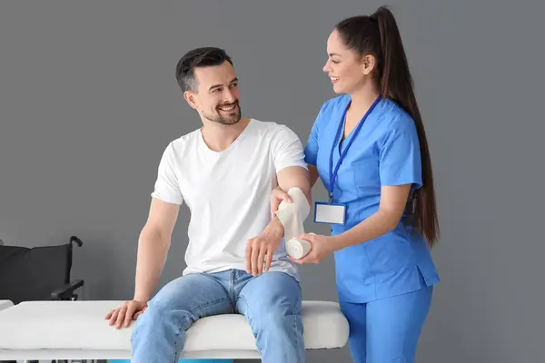 stock image Female physiotherapist applying bandage onto arm of young man in rehabilitation center