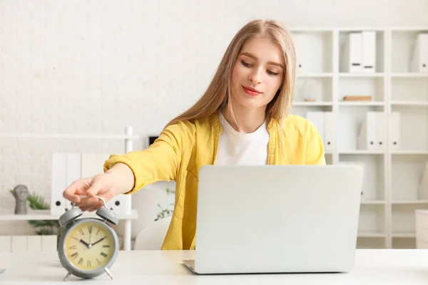 Young businesswoman with alarm clock in office