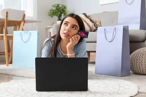 Young woman with credit card and laptop shopping online at home