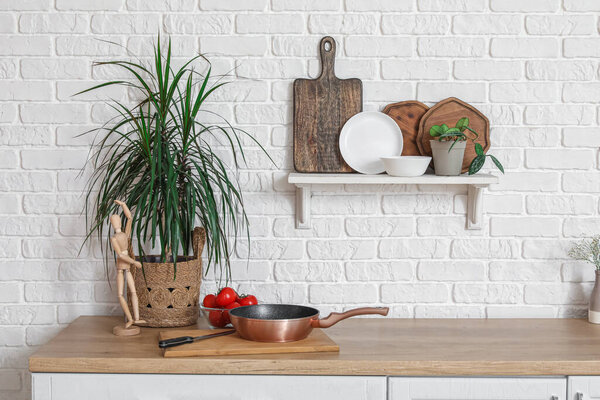 Деревянные столешницы с раскройными досками, карнизом, манекеном и сковородкой на современной кухне