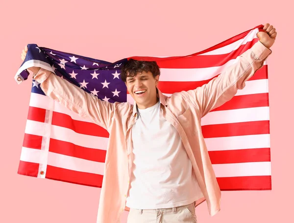 Happy young man with USA flag on pink background