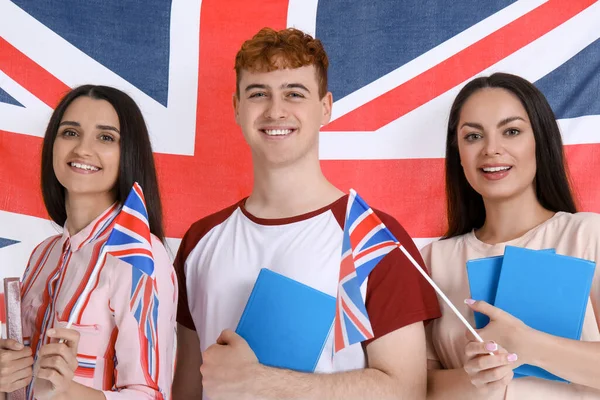Young students of language school with books against UK flag