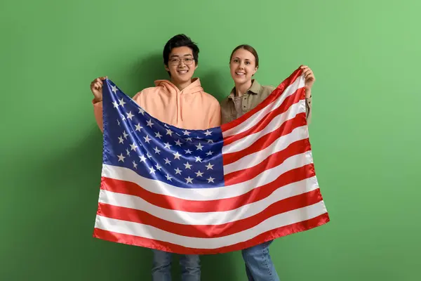 Young students of language school with USA flag on green background