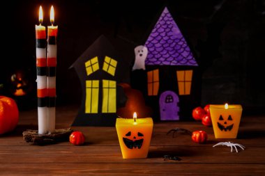 Farklı yanan mumlar ve ahşap masada Cadılar Bayramı dekoru olan kompozisyon