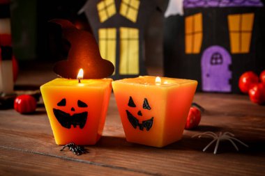 Cadılar Bayramı kutlaması için balkabağı şeklinde yanan mumlarla ahşap masada yakın plan kompozisyon.