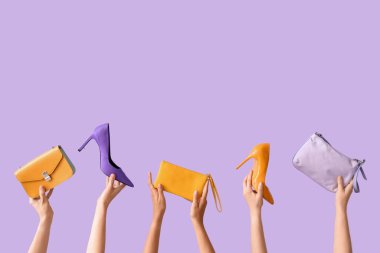 Farklı tarz çantalar tutan kadın eller ve leylak arka planda yüksek topuklar.