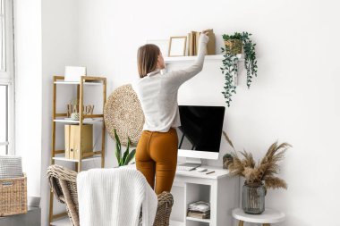 Ofisteki raflardan kitap alan genç bir kadın.