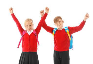 Beyaz arka planda sırt çantaları olan şık üniformalı küçük sınıf arkadaşları.