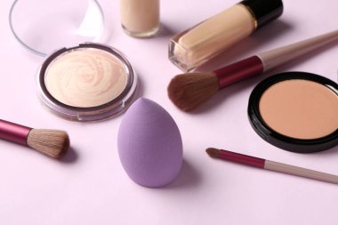 Leylak arka planında makyaj aksesuarları ve kozmetik ürünleri, yakın plan