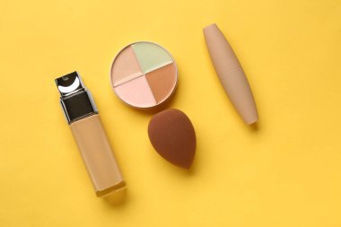 Sarı arka planda dekoratif kozmetik ve makyaj süngeri olan kompozisyon