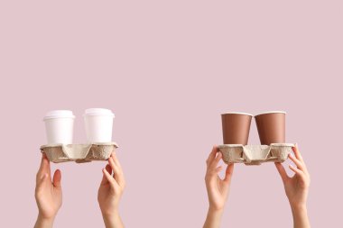 Farklı paket kâğıt bardaklara ve mor arka planda tutuculara sahip kadın elleri