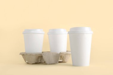 Bej arka planda tutacağı olan beyaz paket kağıdı bardakları