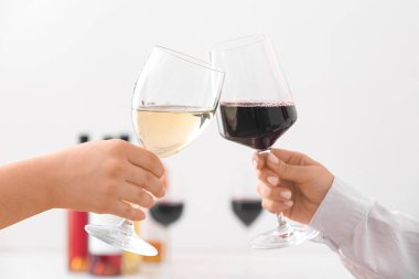 Aydınlık arka planda farklı şaraplardan yapılmış kadehlerle kadın elleri.