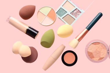 Pembe arka planda uçan makyaj malzemeleri ve kozmetik ürünleri
