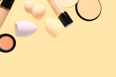 Renkli arka planda uçan makyaj süngerleri ve dekoratif kozmetik ürünleri