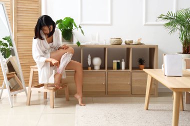 Genç Asyalı kadın evde tıraş olurken tıraş oluyor.