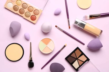 Pembe arka planda farklı makyaj ürünleri