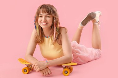 Pembe arka planda yatan kaykaylı genç bir kadın.