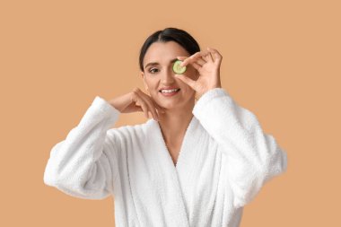 Bej arka planda salatalık dilimi olan genç bir kadın.