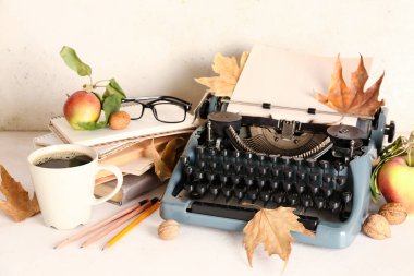 Klasik daktilo, elmalar, kitaplar, bir fincan kahve, fındık, gözlük ve sonbahar yaprakları beyaz arka planda