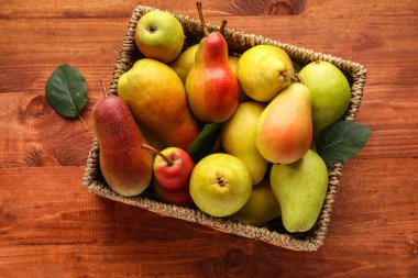 Ahşap zemin üzerinde olgun armutlar olan hasır kutu.