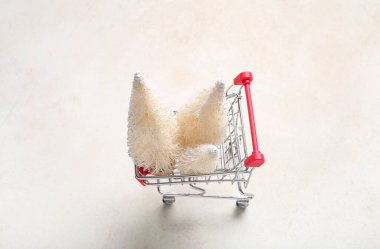 Bej arka planda beyaz Noel ağaçları olan alışveriş arabası.