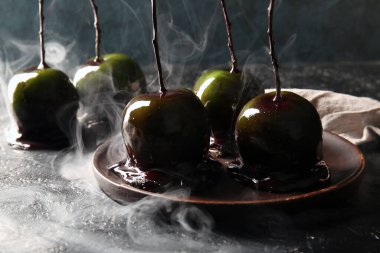 Siyah arka planda Cadılar Bayramı için lezzetli karamelli elma tabağı.
