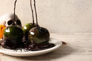 Cadılar Bayramı için lezzetli karamelli elma tabağı ve masada örümcekler.