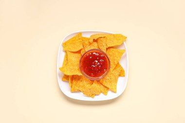 Sarı arka planda lezzetli nachos ve salsa soslu tabak.