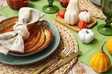 Yeşil masa örtüsü üzerinde balkabaklarıyla servis edilen sonbahar masası, yakın plan.