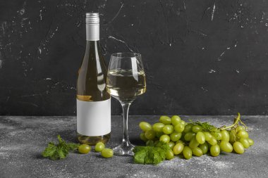 Üzüm ve şarap şişesi. Gri arka planda boş etiket var.