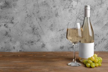 Ahşap arka planda boş etiketli üzüm ve şarap şişesi.