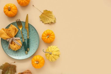 Bej arkaplanda balkabakları ve kurumuş yapraklarla sonbahar masa ayarları