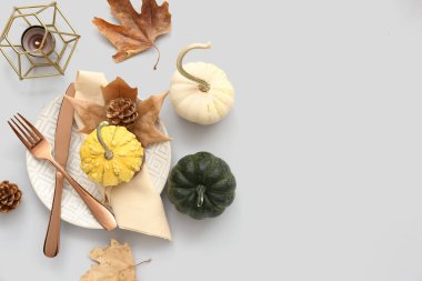 Balkabakları, kurumuş yapraklar ve beyaz arka planda yanan mumlarla sonbahar masası ayarları