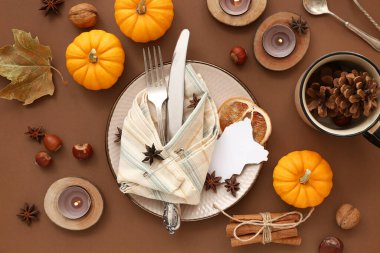 Kahverengi arka planda balkabakları, baharatlar ve yanan mumlarla sonbahar masası ayarları