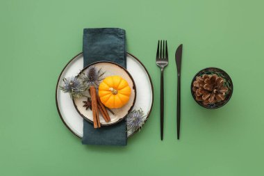 Balkabağı, kurumuş çiçekler ve yeşil arka planda farklı baharatlarla sonbahar masası.