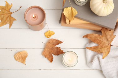 Sonbahar yapraklı mumlar, balkabağı ve beyaz ahşap zemin üzerine kitaplar yakmak.