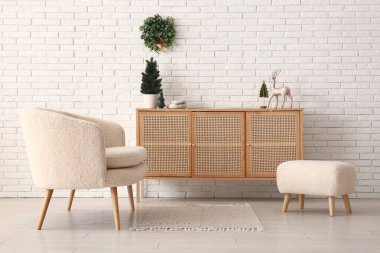 Beyaz koltuğu, ahşap dolabı ve Noel süslemeleri olan festival salonu.