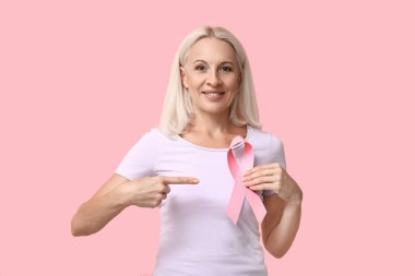 Pembe arka planda kurdeleli olgun bir kadın. Göğüs kanseri farkındalığı konsepti