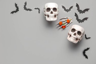 Kadife çiçekleri, yarasalar ve gri arka planda iskelet elli insan kafatasları.