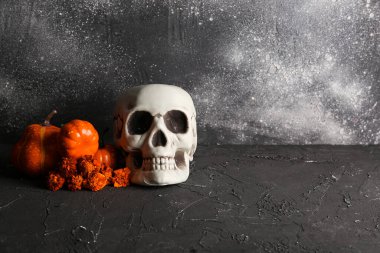 Kadife çiçekli insan kafatası ve grunge siyah arka planda balkabağı