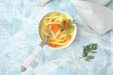 Mavi arka planda bir kase lezzetli tavuk çorbası.