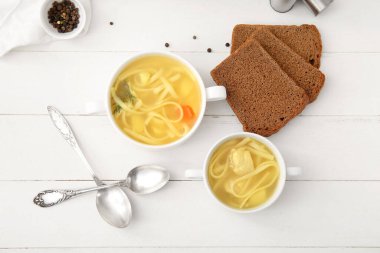 Beyaz ahşap arka planda lezzetli tavuk çorbası ve ekmek.