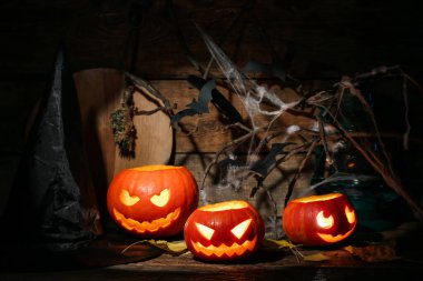 Cadılar Bayramı kompozisyonu, kriko-fenerler, cadı şapkası, yarasalar ve ahşap masa üzerinde ağ