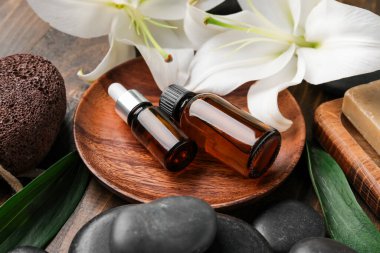 Kozmetik ürünleri şişeleri, spa aksesuarları ve ahşap arka planda zambak çiçekleri olan kompozisyon, yakın plan