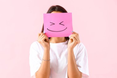 Pembe arka planda kağıt gülüşü olan genç bir kadın.
