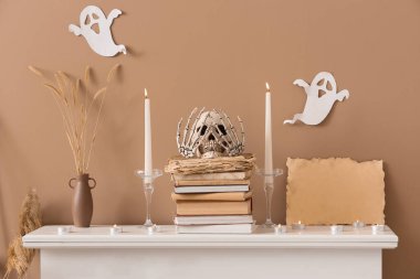 Cadılar Bayramı kafatası olan şömine rafı, yanan mumlar ve hayaletler.