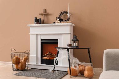 Cadılar Bayramı süslemeleri ve bej duvarın yanında balkabaklarıyla şömine.