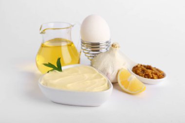 Bir kase taze mayonez ve beyaz arka planda malzemeler.