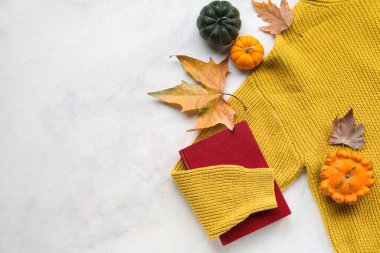Açık arkaplanda kalın giysiler, kitap ve balkabaklarıyla kompozisyon